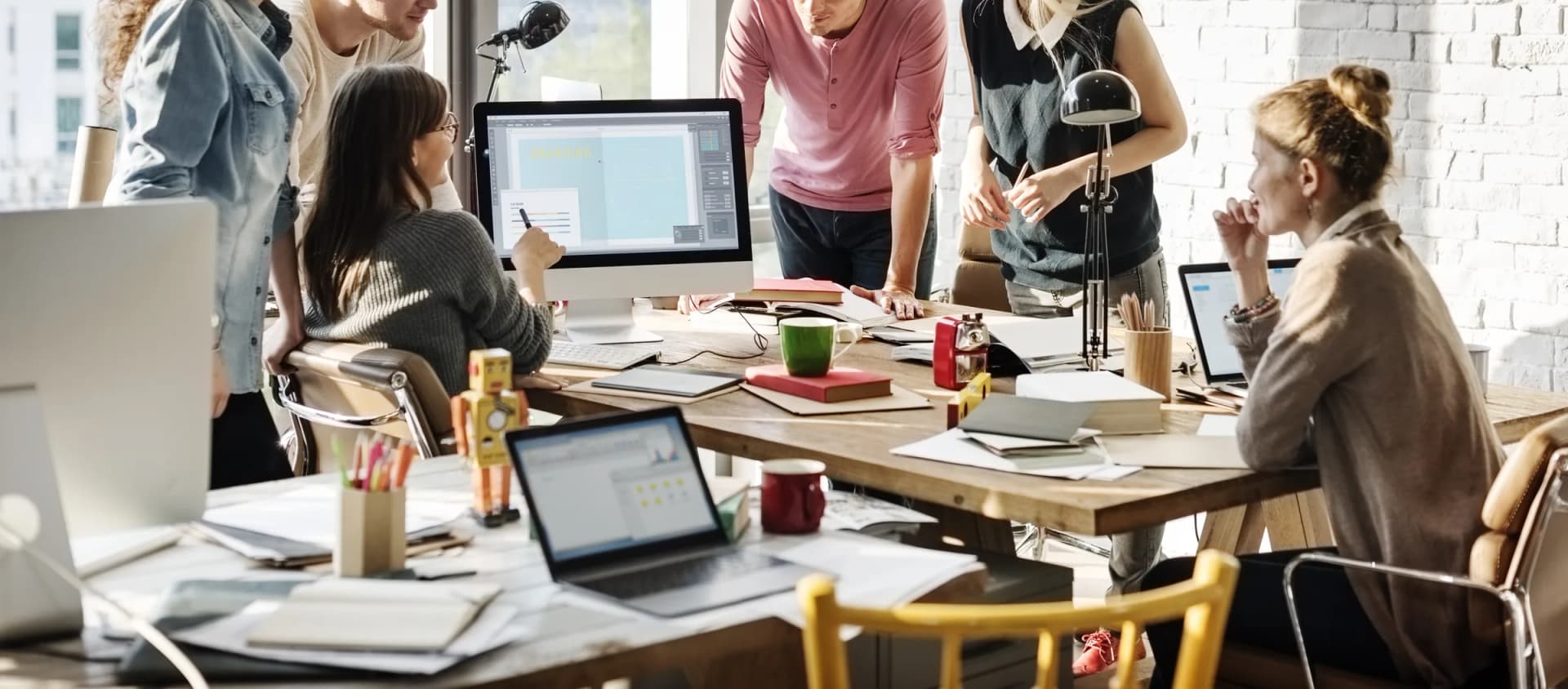 Equipo de trabajo revisando contenido en laptops alrededor de una mesa